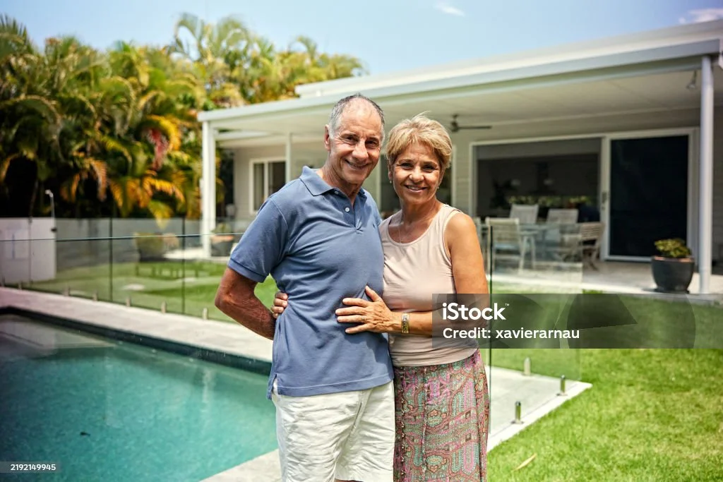 A couple standing in their backyard beside their pool